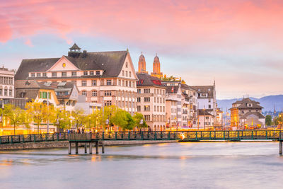 Buildings at waterfront against cloudy sky