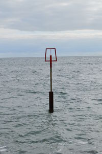 Lifeguard hut on wooden post in sea against sky