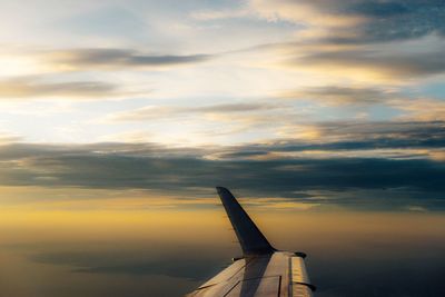 Airplane wing against sky during sunset