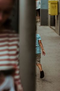 Rear view of boy walking on street in city