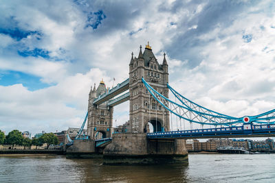 Low angle view of tower bridge against cloudy sky