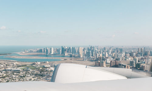 Cropped image of airplane over cityscape against sky