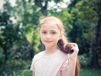 Portrait of smiling young woman against trees