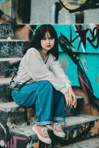 Portrait of woman sitting on wall