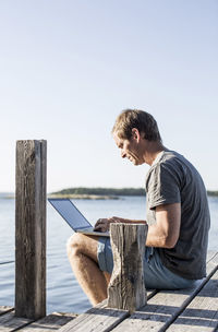 Side view of mature man using laptop on pier