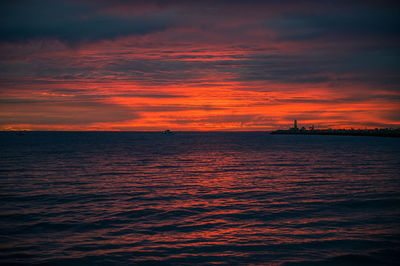 Scenic view of sea against dramatic sky during sunset