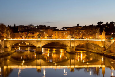 Reflection of arch bridge over river in city