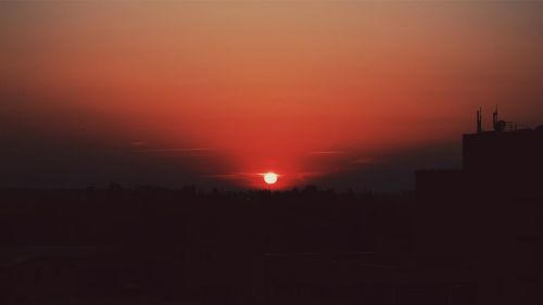 Silhouette city against sky during sunset