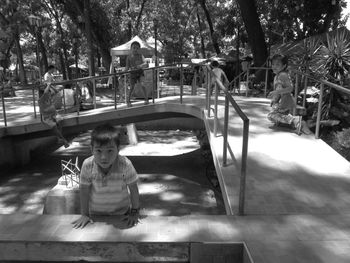 Boy sitting in swimming pool against trees