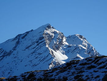 Snowcapped mountains against clear blue sky