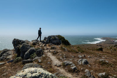 Person standing at end of coastal trail looking over pacific ocean