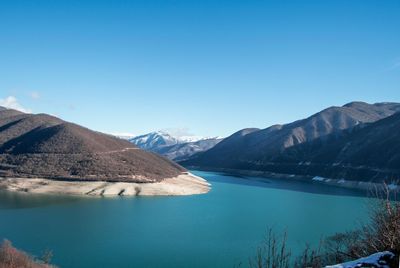 Scenic view of lake and mountains against clear blue sky