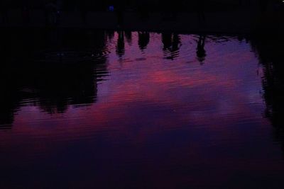 Reflection of silhouette trees in lake at night