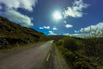 Road amidst landscape against cloudy sky