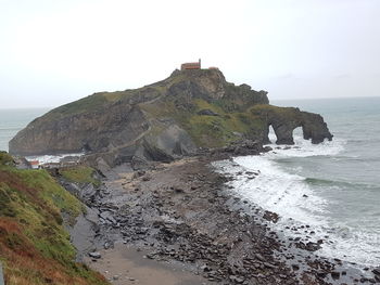 Scenic view of cliff by sea against clear sky