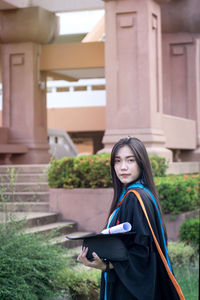 Portrait of woman standing against building