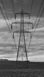 Electricity pylon on field against sky