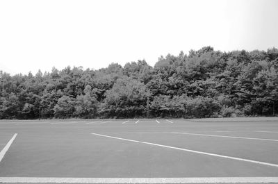 Empty road by trees against sky