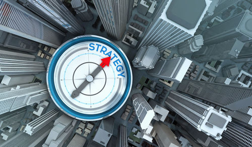 Digital composite image of navigational compass with strategy text and cityscape