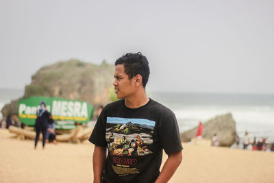 Man standing at beach against sky