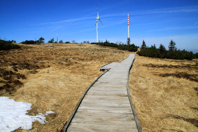 Dirt road amidst field against sky