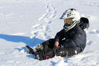 Person sitting on snow covered field