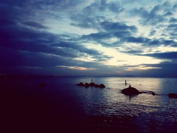 Silhouette people on beach against sky during sunset