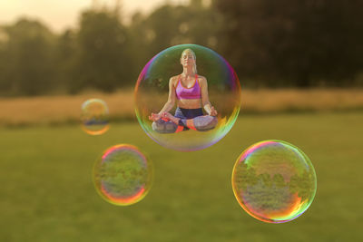 Digital composite image of woman doing yoga in bubble