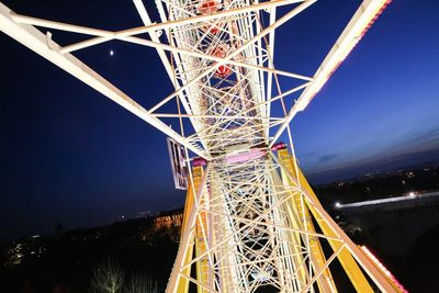 Low angle view of illuminated electricity pylon against clear sky at night