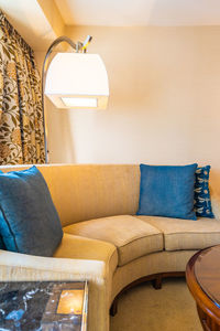 Close-up of illuminated lamp over sofa at hotel room