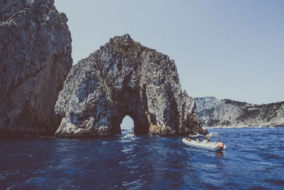 Rock formations in sea against clear sky