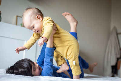 Side view on two children playing with each other on the parent's bed