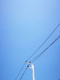 Low angle view of power cables against clear blue sky