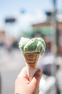 Cropped hand holding ice cream cone in city