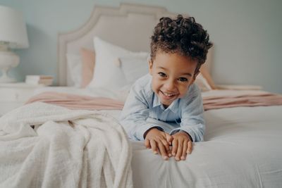 Portrait of smiling boy lying on bed at home