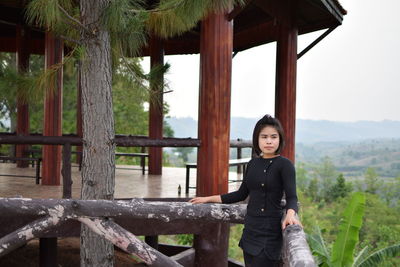 Young woman looking away while standing by railing on observation point against sky