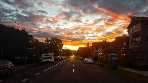 Cars on road against sky at sunset