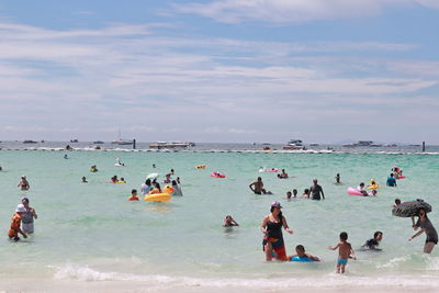 People enjoying at beach against sky