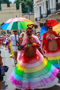 People holding multi colored umbrellas on street in city