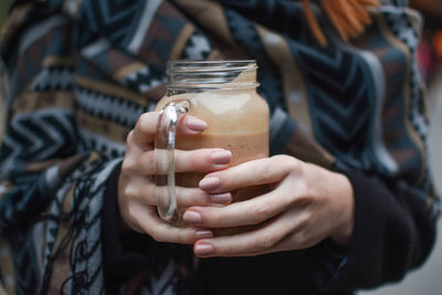 Midsection of woman holding smoothie in mason jar