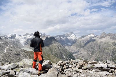 Rear view of man standing on mountain against sky