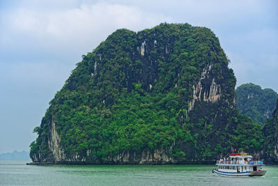 Tourist junk floating along limestone rocks in ha long bay, vietnam