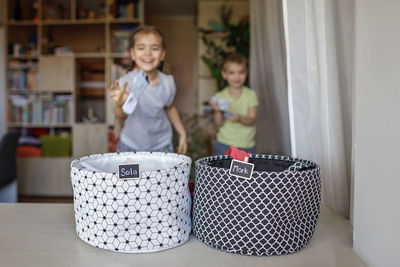 Cute kids throwing garment in basket on table