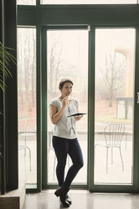 Full length of thoughtful businesswoman with notepad and pen in office