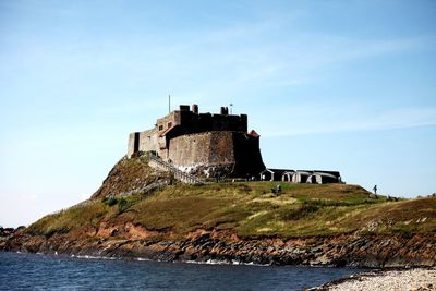 Old building by sea against sky