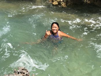 High angle portrait of smiling young woman swimming in water
