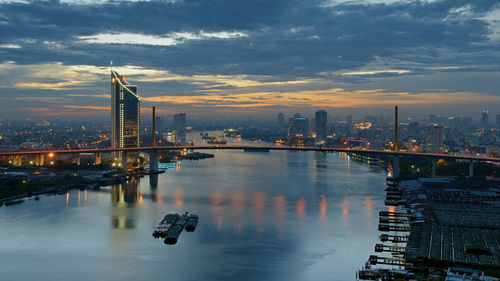 Rama ix bridge over chao phraya river against cloudy sky during sunset in city