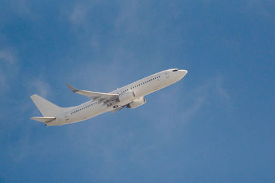 Low angle view of airplane flying against blue sky