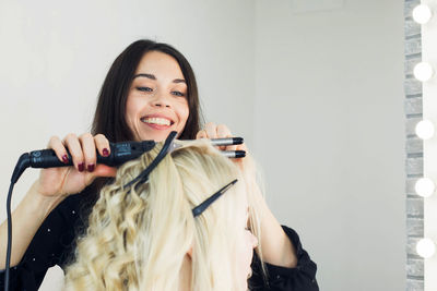 Hairdresser using curling tongs on customer