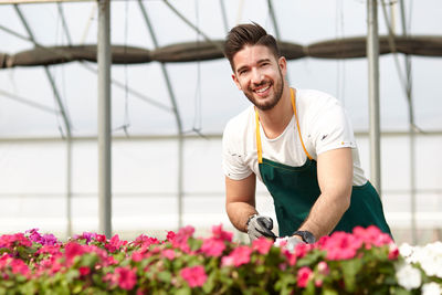 Young man smiling while standing by flowering plants